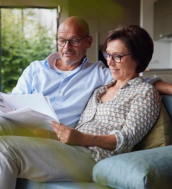 Man and woman sitting on couch and looking at papers